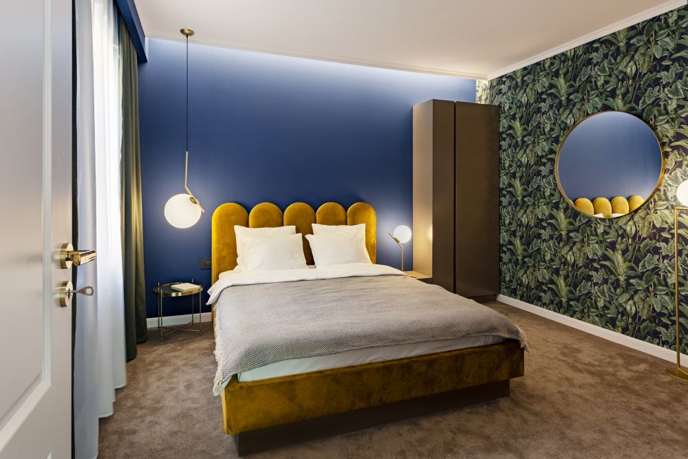 dormitor apartament 2 camere semidecomandat combinatie de culori pentru albastru auriu verde bej pat auriu tapet verde model exotic perete albastru