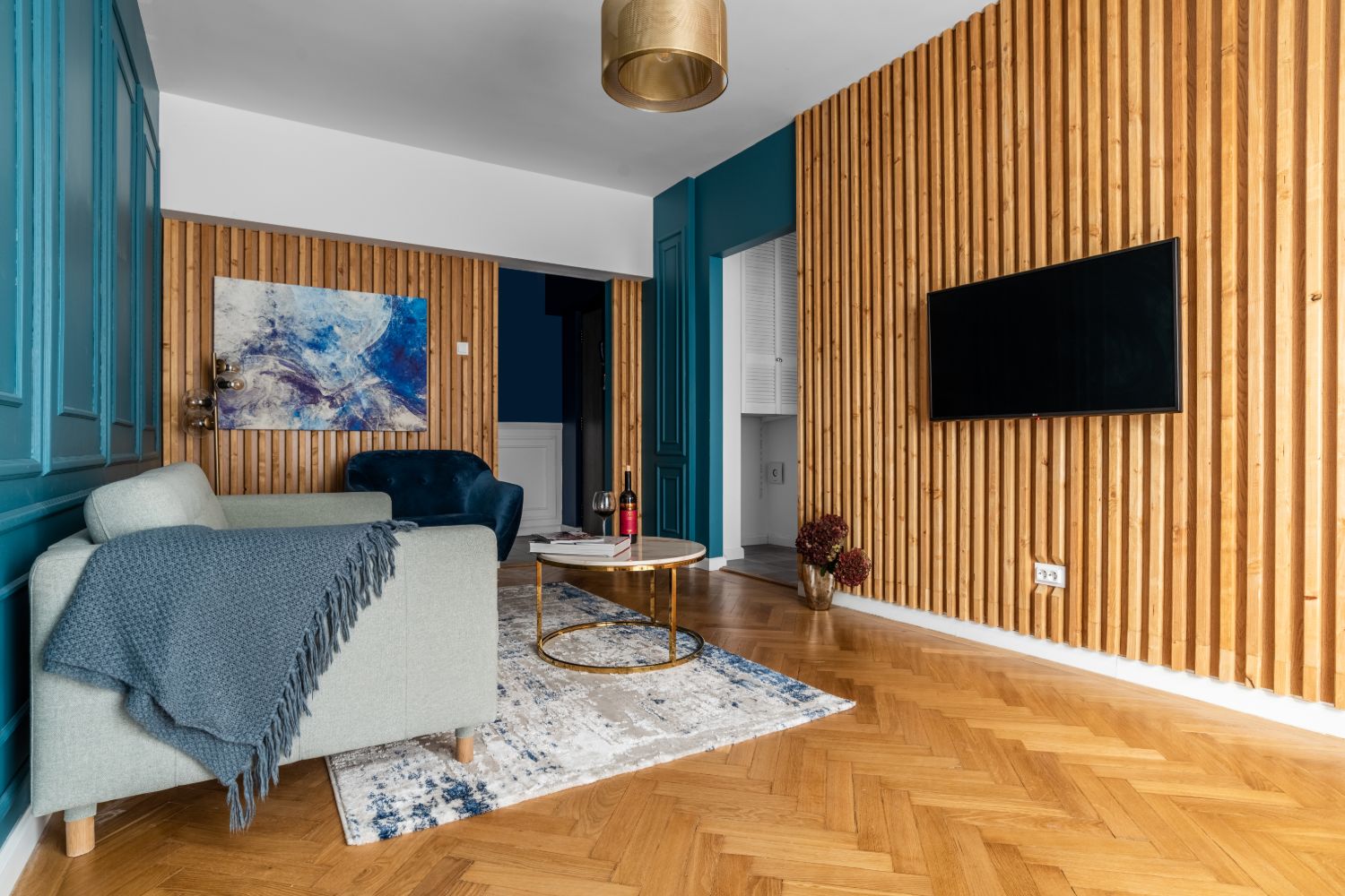 living perete riflaj lemn vopsea albastra lambriuri parchet lemn natur model chevron corp de iluminat auriu