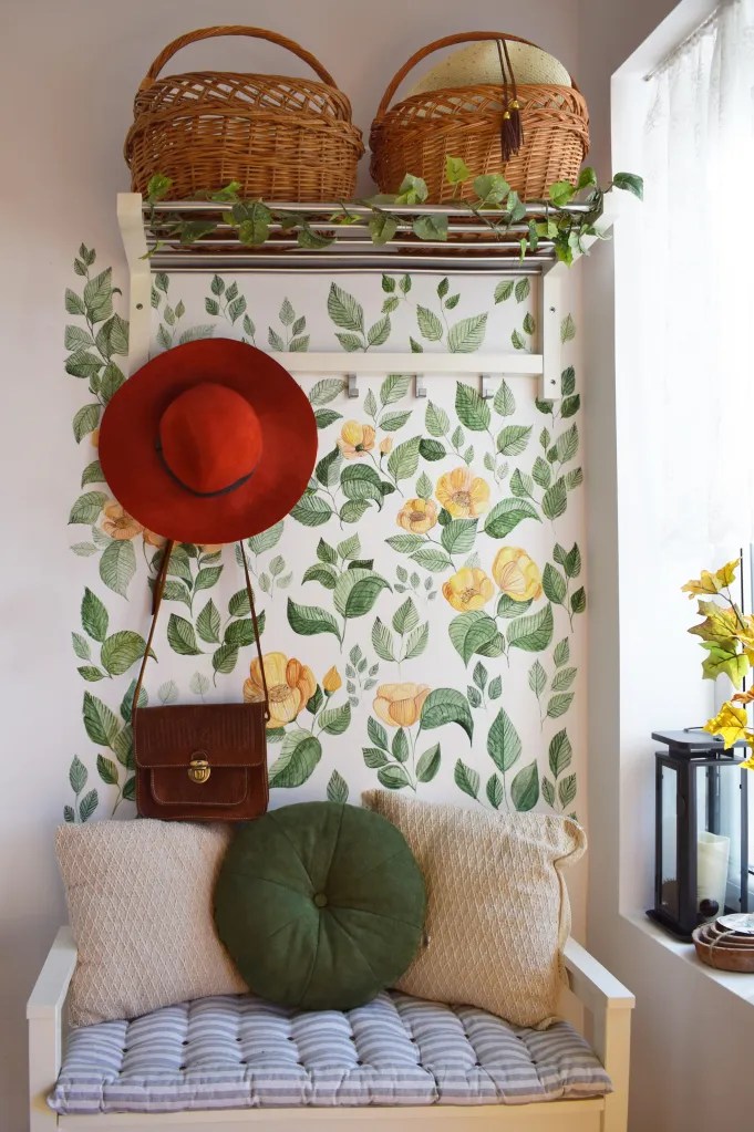amenajare modernă hol cu pereți pictați cu frunze și flori băncuță din lemn cu perne decorative cuier metalic cosuri din iuta pentru accesorii
