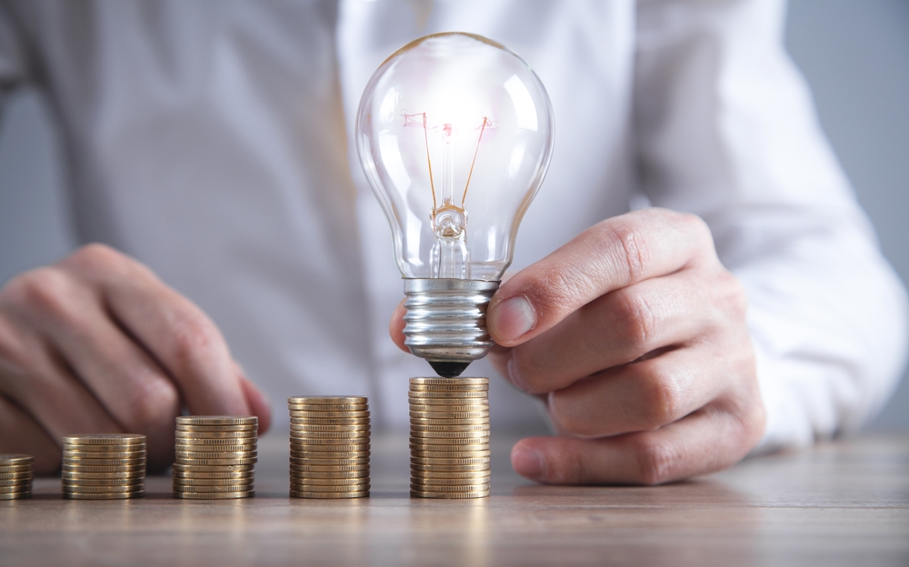 bărbat tine un bec pe grămadă de monede ilustrație idee economisire energie electrica