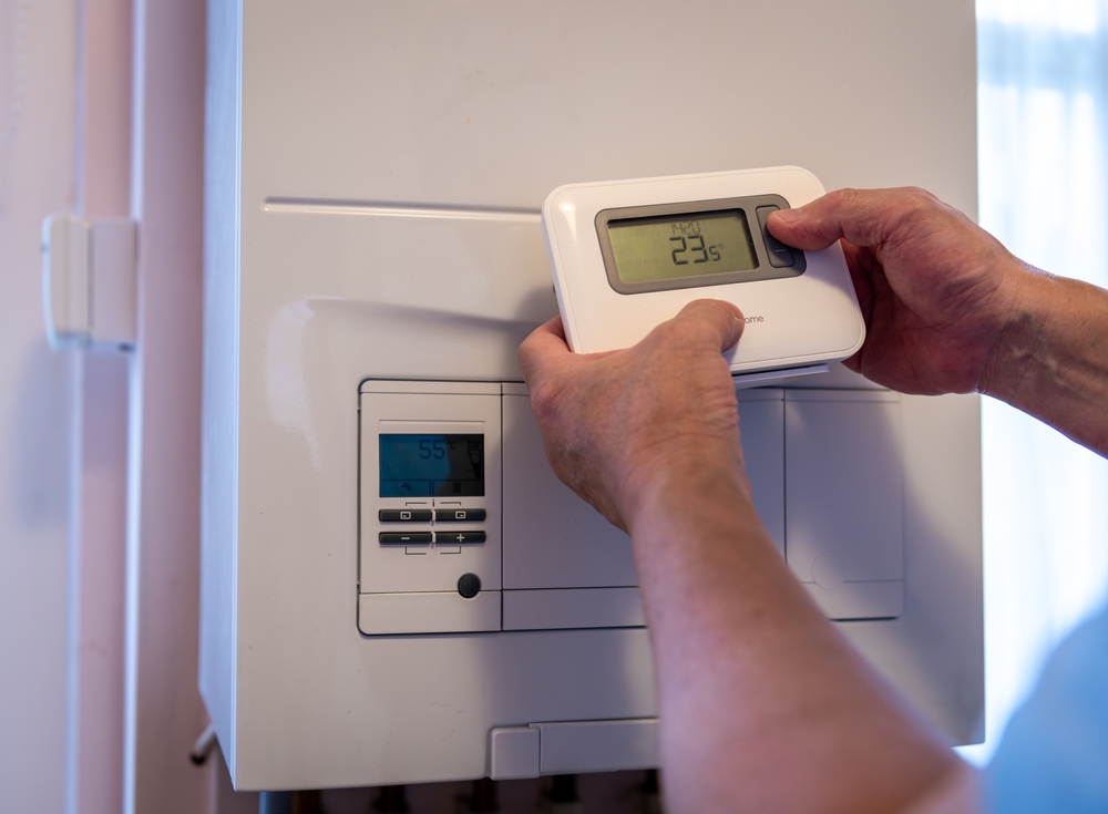 bărbat cu termostat in mana îl resetează pentru funcționarea centralei termice