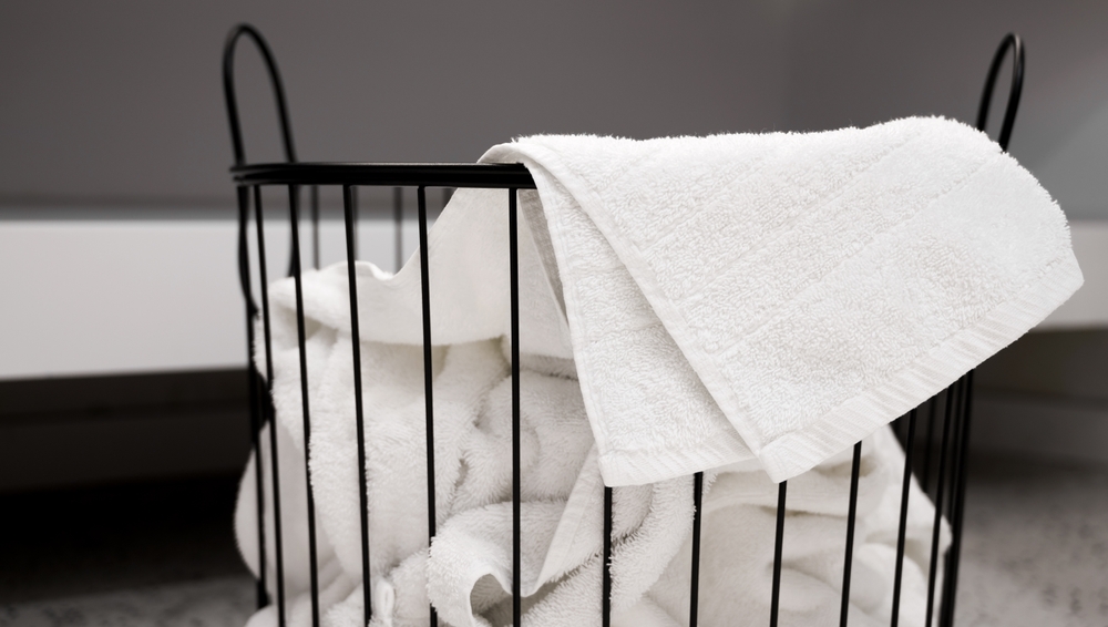 La cât timp se spală prosoapele de față: Prosoape albe de față într-un coș de rufe metalic negru. 