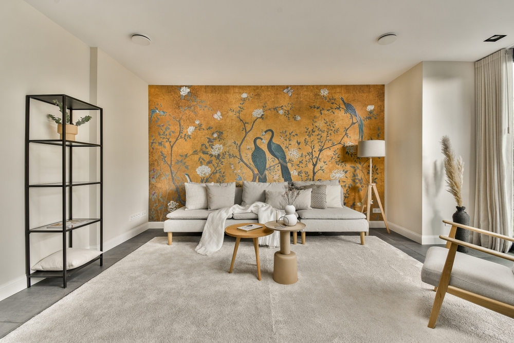 amenajare showroom living cu set de mobilier canapea si fotoliu la fel si tapet auriu oranj cu păsări și crengi de copac